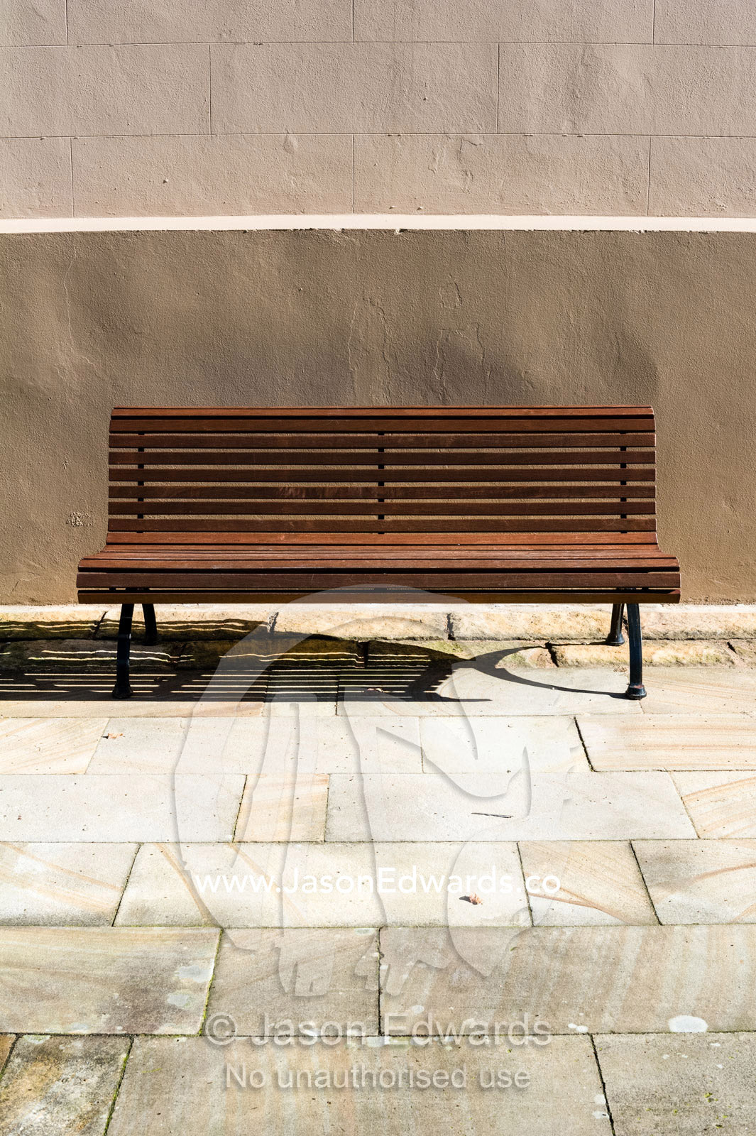 A park bench in a sandstone courtyard is a place to rest in the sun. The Sydney Mint, Sydney, New South Wales, Australia.