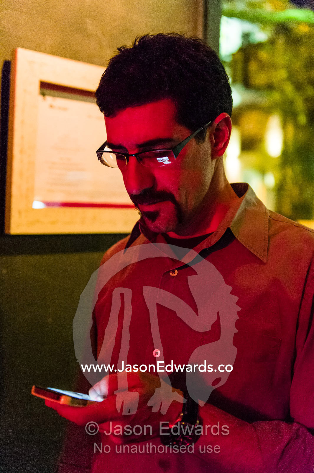 A man sends a text message outside an inner city bar and restaurant. Darlinghurst, Sydney, New South Wales, Australia.