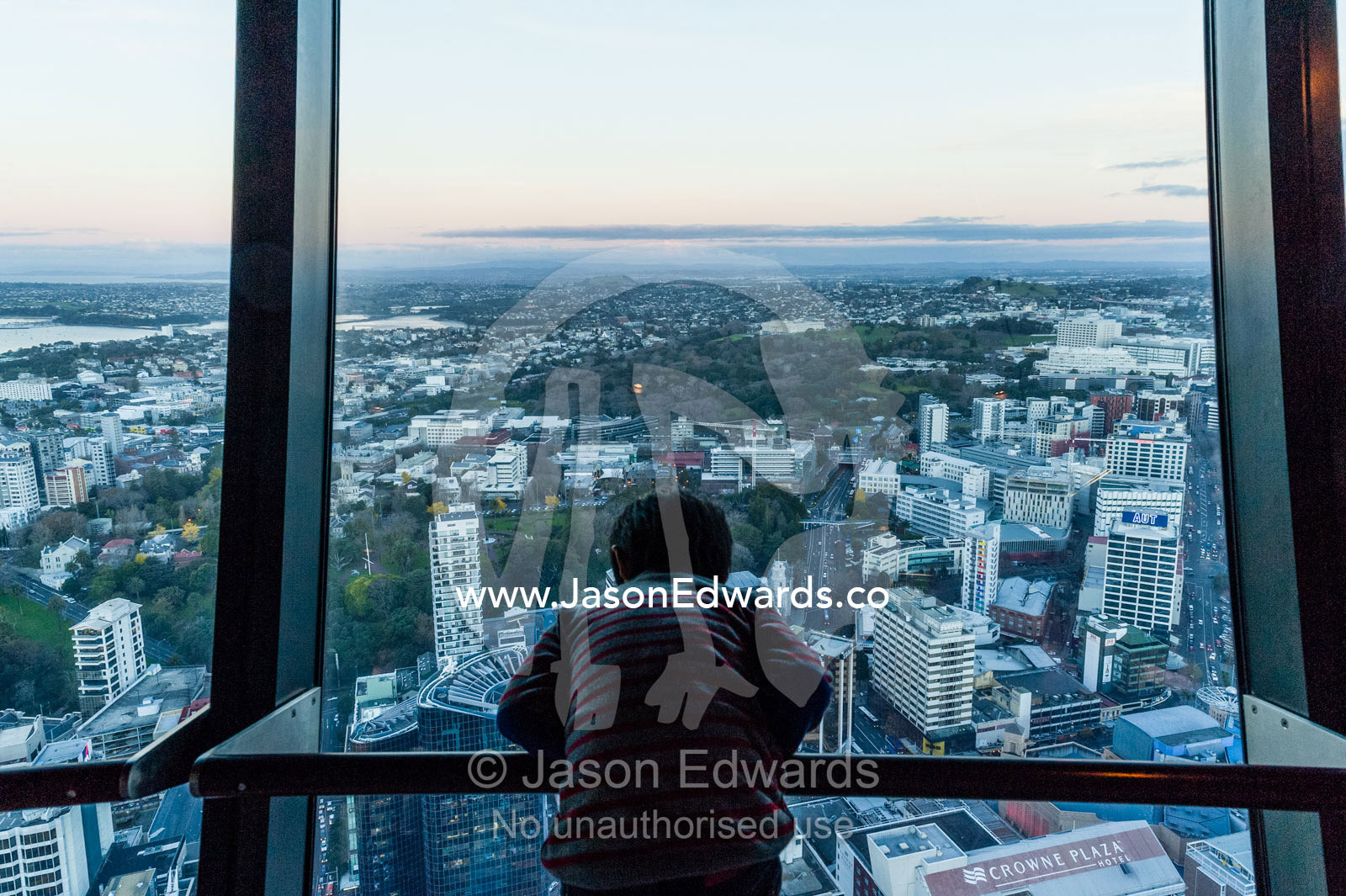 A small boy looks down on Auckland city from the top of the Sky Tower. Sky Tower, Auckland City, Auckland, New Zealand.