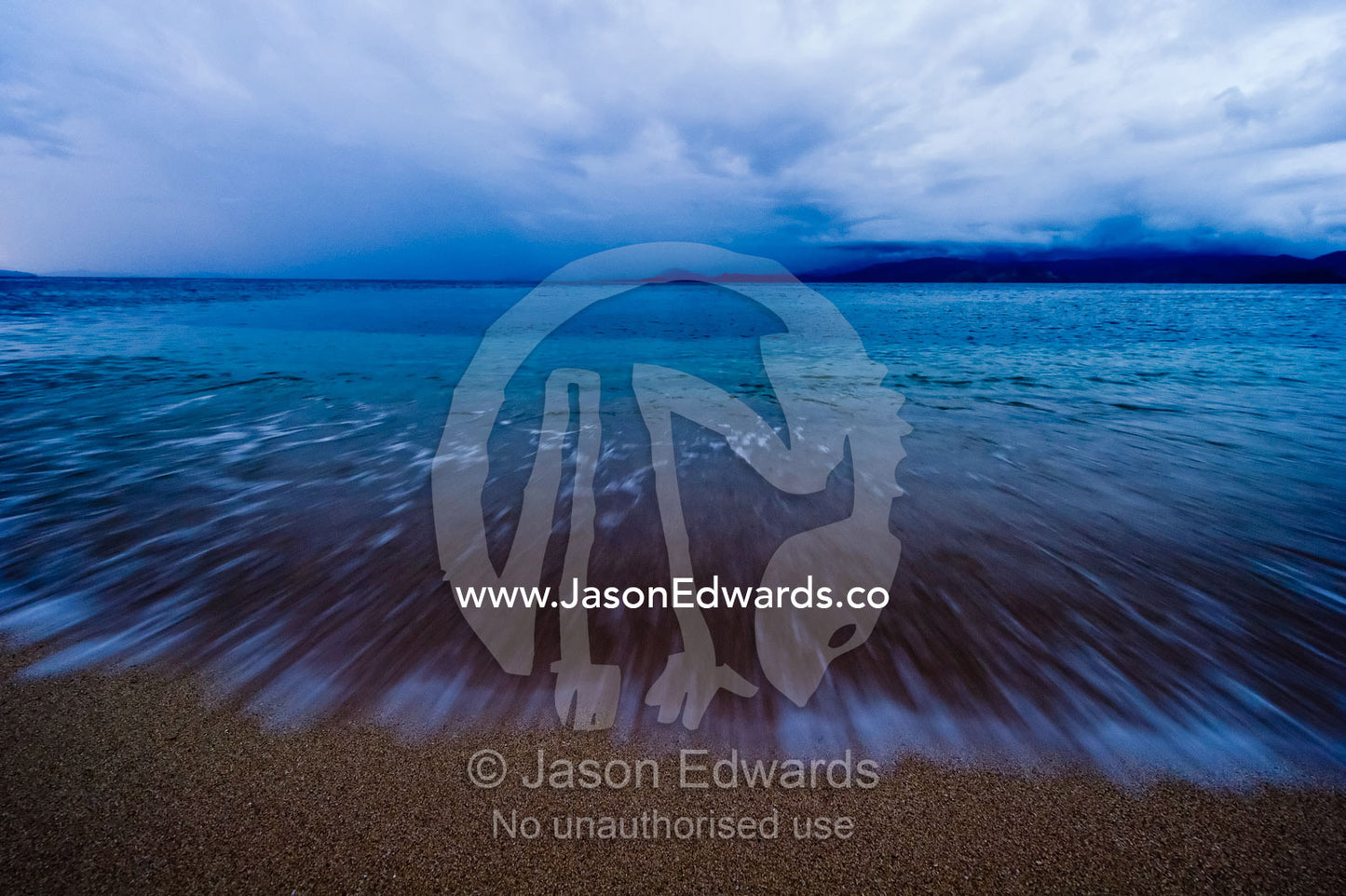 Storm clouds block out stars as waves lap a deserted beach at night. Rabi Island, Somosomo Strait, Pacific Ocean, Fiji Islands.