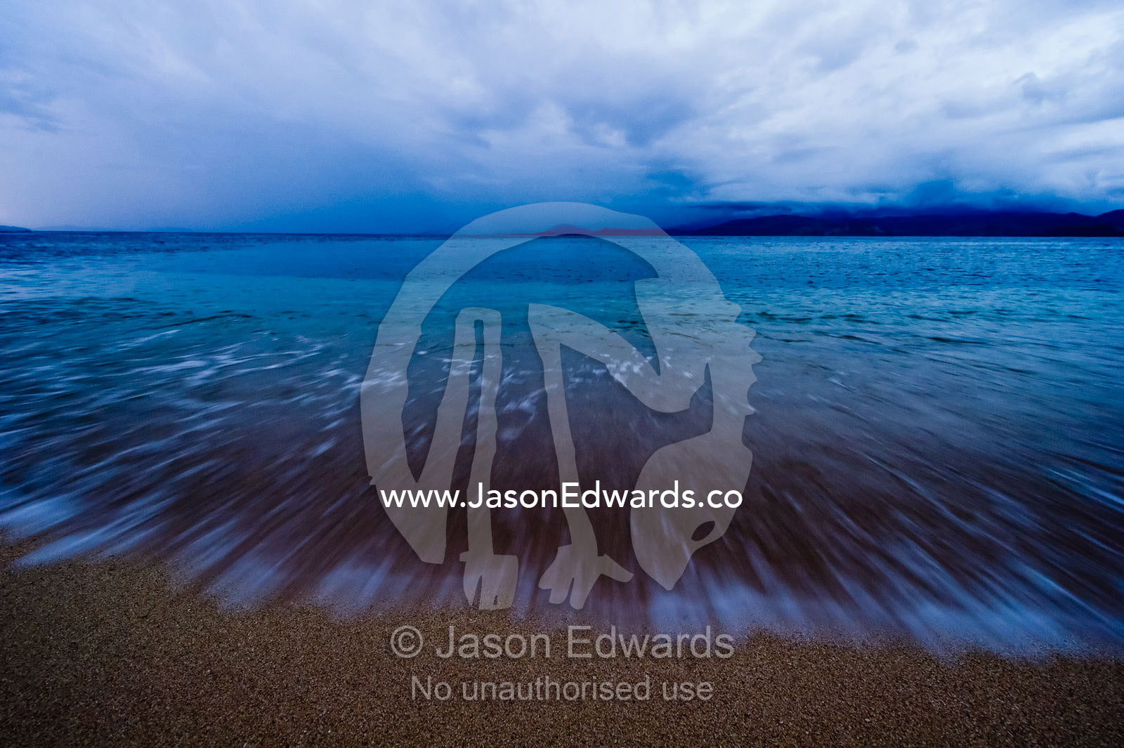 Storm clouds block out stars as waves lap a deserted beach at night. Rabi Island, Somosomo Strait, Pacific Ocean, Fiji Islands.
