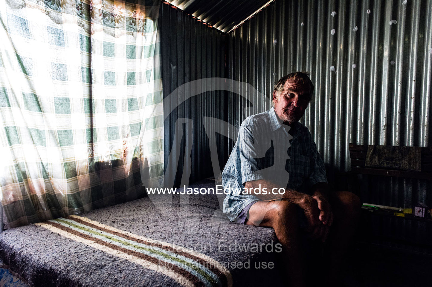 A man sits inside a corrugated tin garden shed that is his home. Bon Accord Dam, Gauteng Province, South Africa.