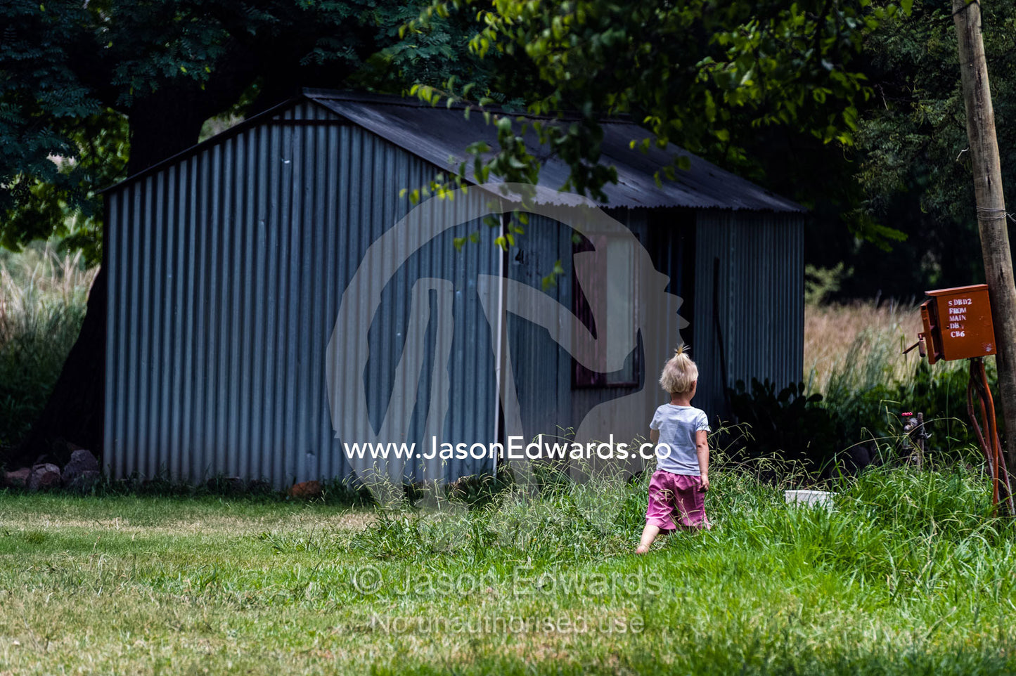 A small girl explores her displaced community of garden shed homes. Bon Accord Dam, Gauteng Province, South Africa.