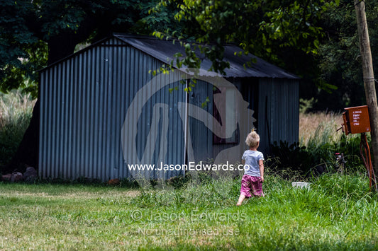 A small girl explores her displaced community of garden shed homes. Bon Accord Dam, Gauteng Province, South Africa.