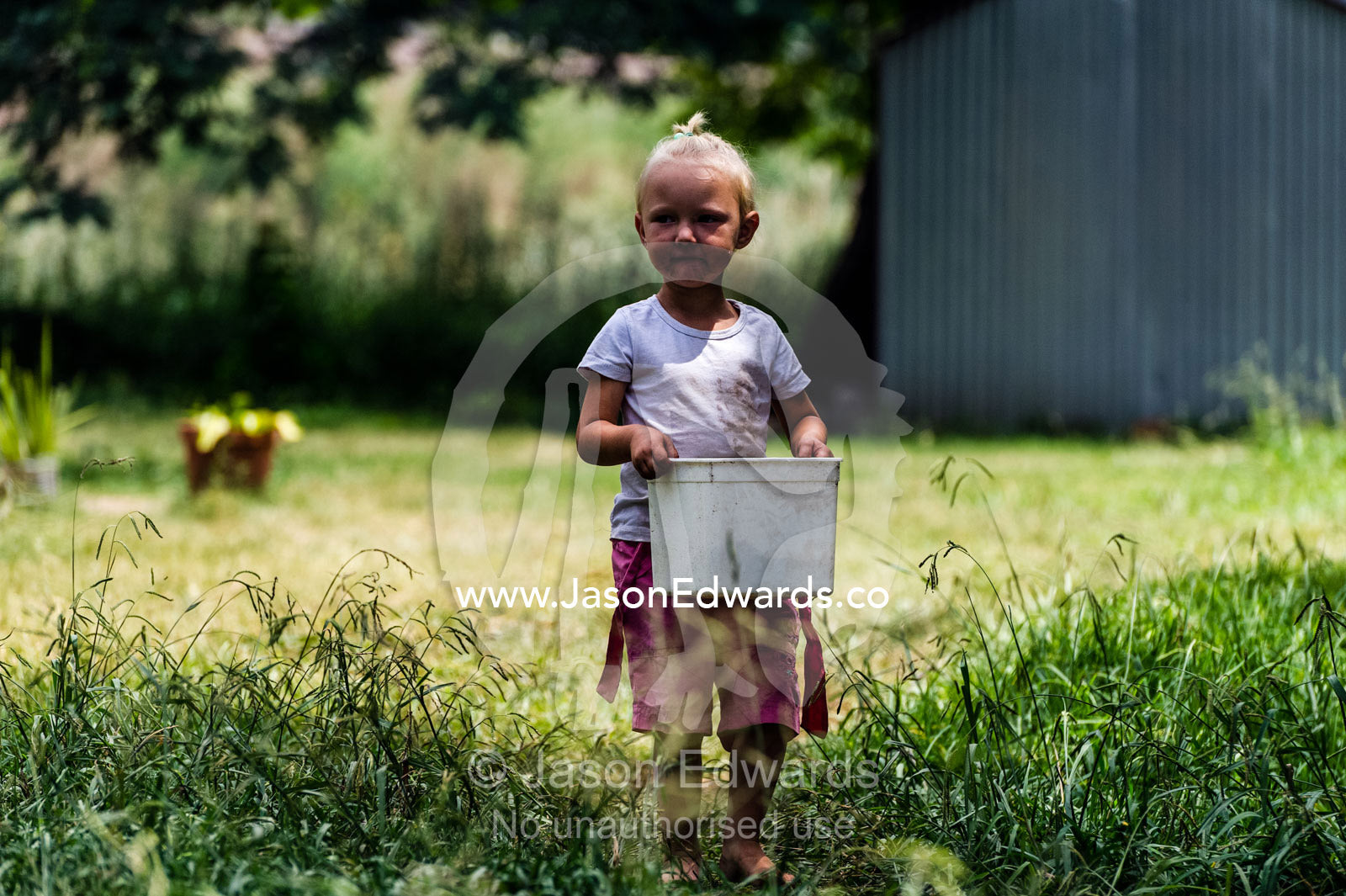 A small girl collects a bucket of water from a communal tap. Bon Accord Dam, Gauteng Province, South Africa.