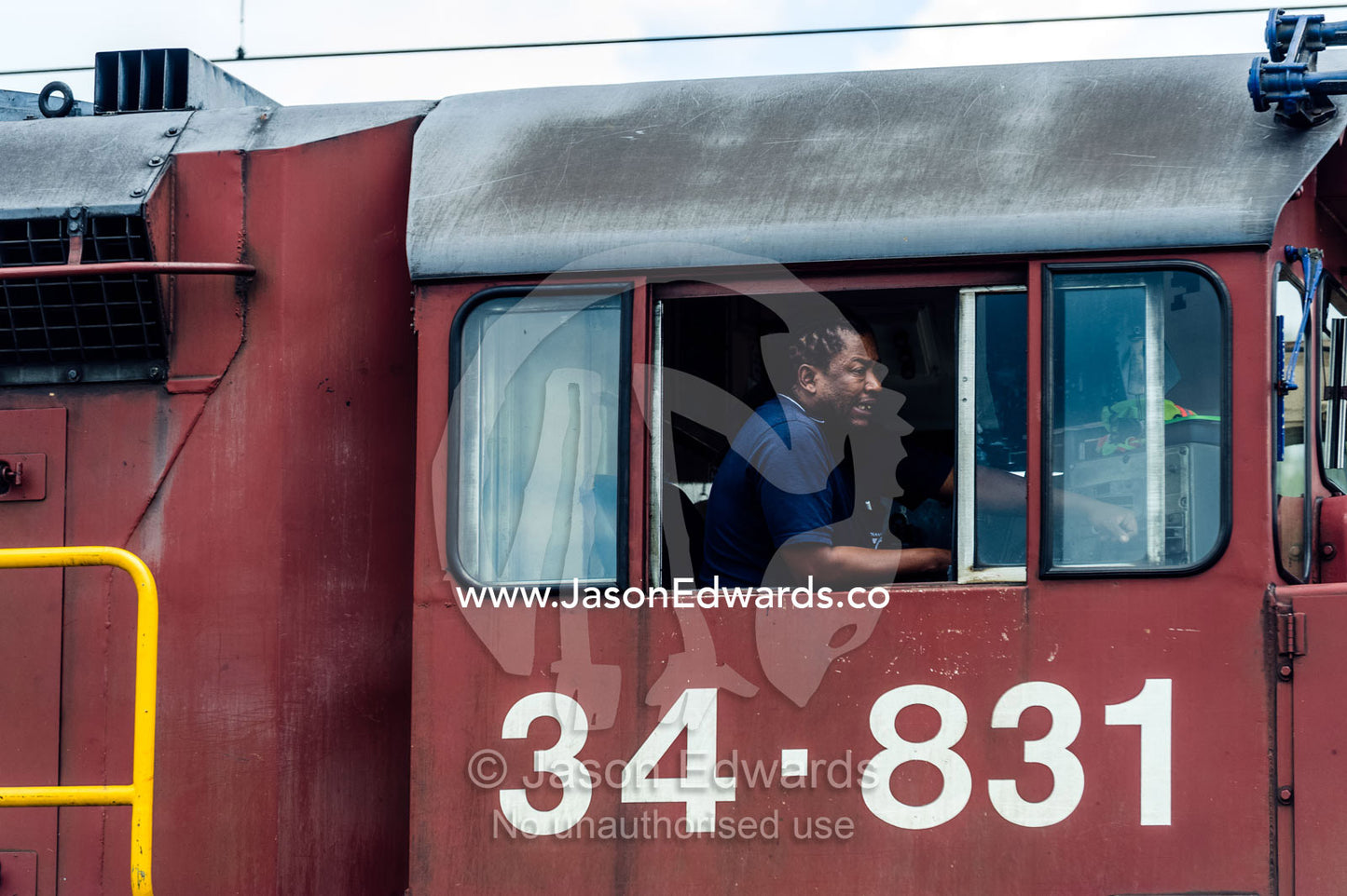 A train driver guides a diesel locomotive over a level crossing. Bon Accord Dam, Gauteng Province, South Africa.