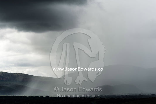 A torrential rainstorm shrouds rolling hills and farmland in grey. Route 101, Naboomspruit, Modimole, Limpopo, South Africa.