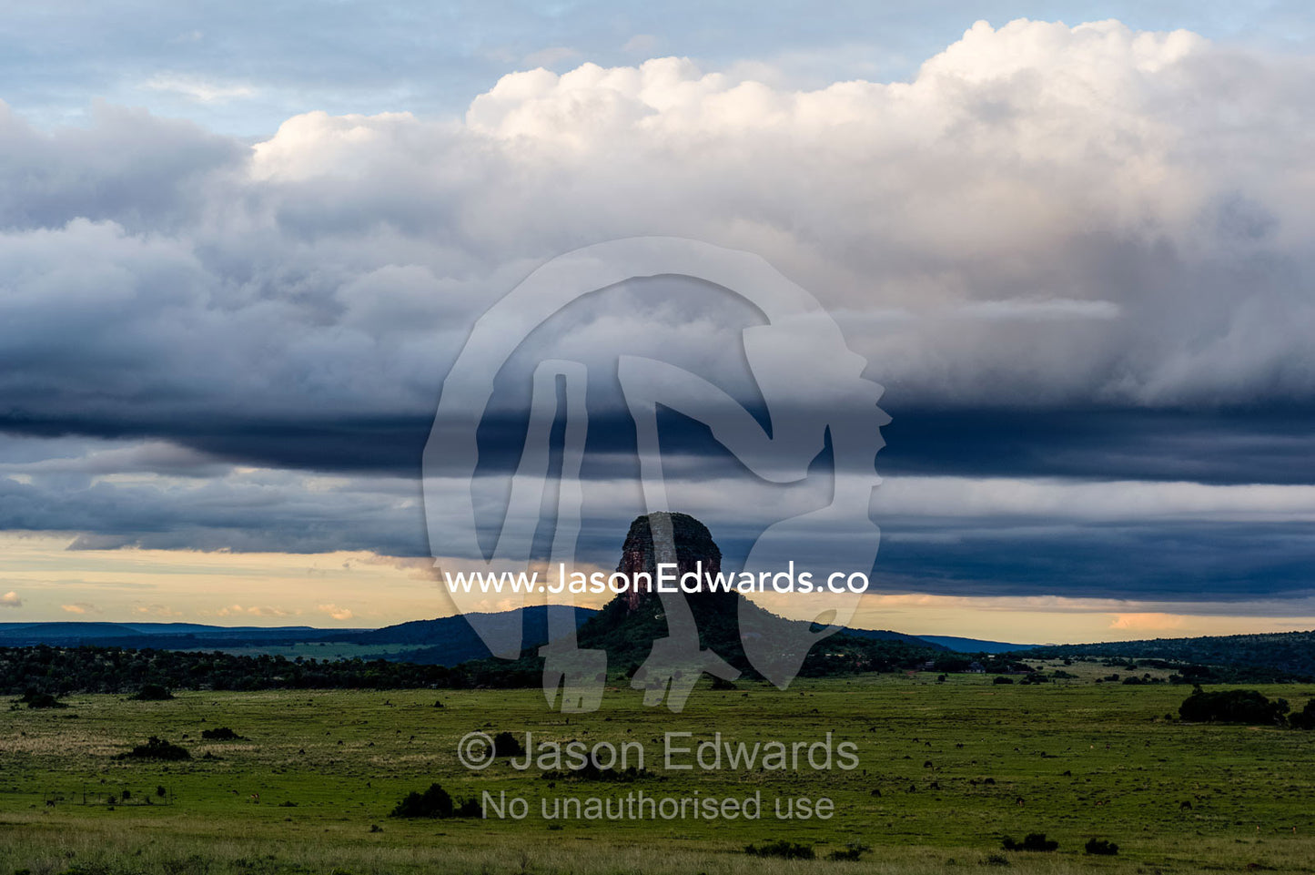Storm clouds swirl above the summit of a solitary mountain on a plain. Entabeni Mountain, Waterberg Mountains, Entabeni Game Reserve, Limpopo Province, South Africa.