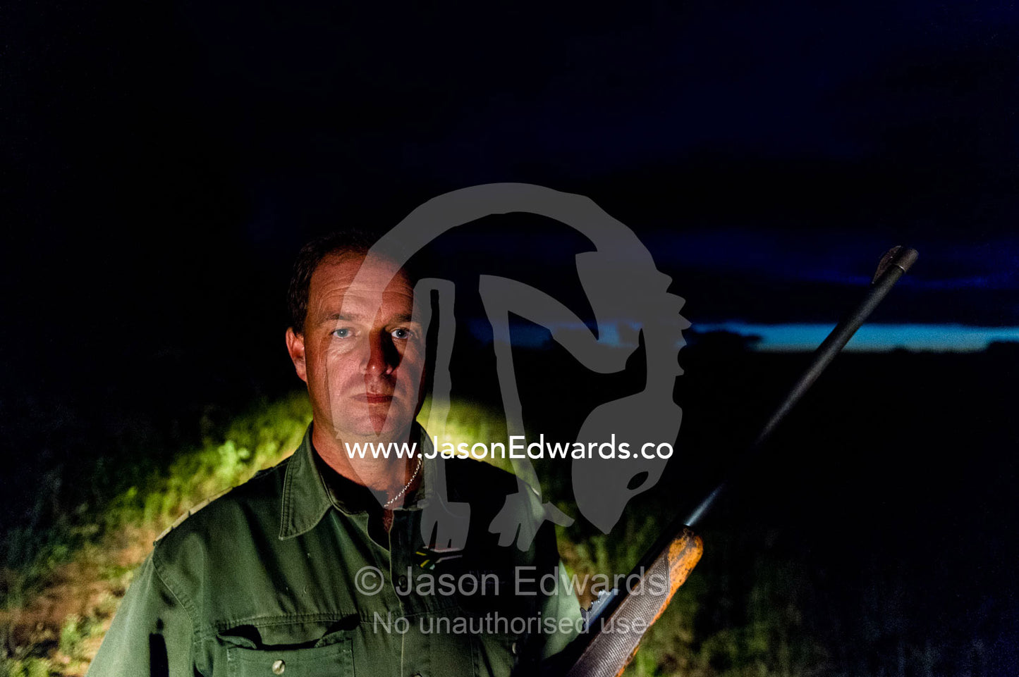 A national park ranger with his rifle patrols the savannah at night. Waterberg Mountains, Entabeni Game Reserve, Limpopo Province, South Africa.