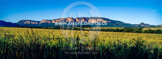 Dawn illuminates the cliffs of a mountain range overlooking farmland. Waterberg Mountains, Entabeni Game Reserve, Limpopo Province, South Africa.