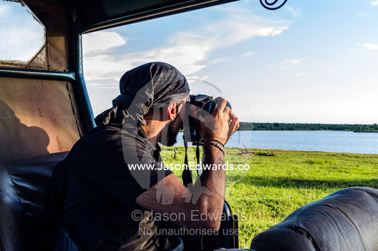 A photographer captures a waterhole at sunset from his safari 4wd. Kruger National Park, Manyeleti Game Reserve, Limpopo Province, Mpumalanga Province, South Africa.