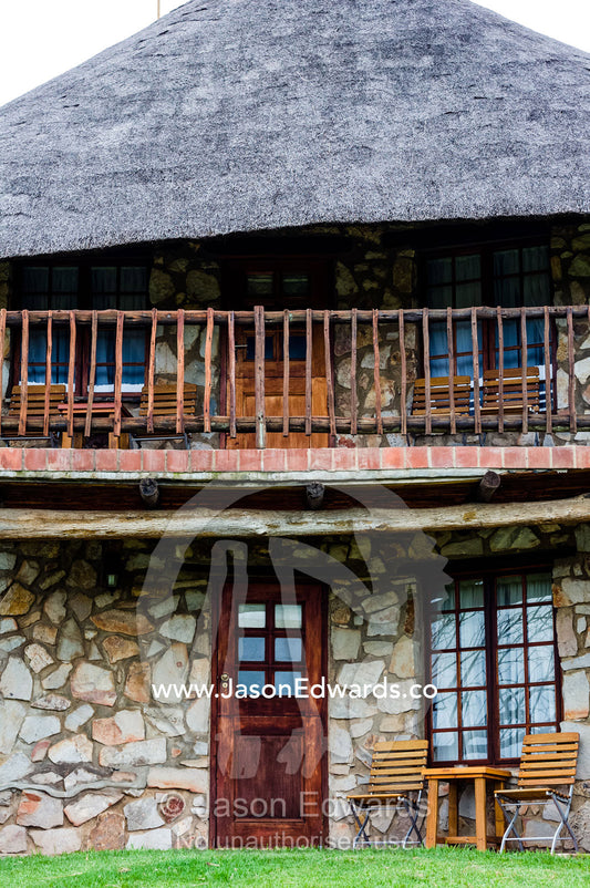 A stone guest bungalow with thatched roof in an African safari lodge. The Farm Inn, Pretoria, Gauteng Province, South Africa.