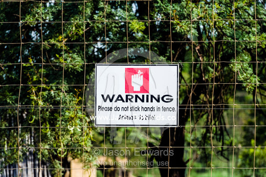 A biting warning sign on a lion cage at an African safari lodge. The Farm Inn, Pretoria, Gauteng Province, South Africa.