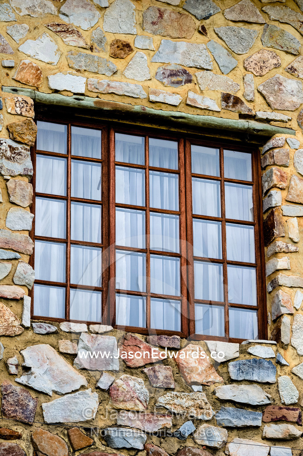 A timber and glass window set in a handmade stone wall at a lodge. The Farm Inn, Pretoria, Gauteng Province, South Africa.