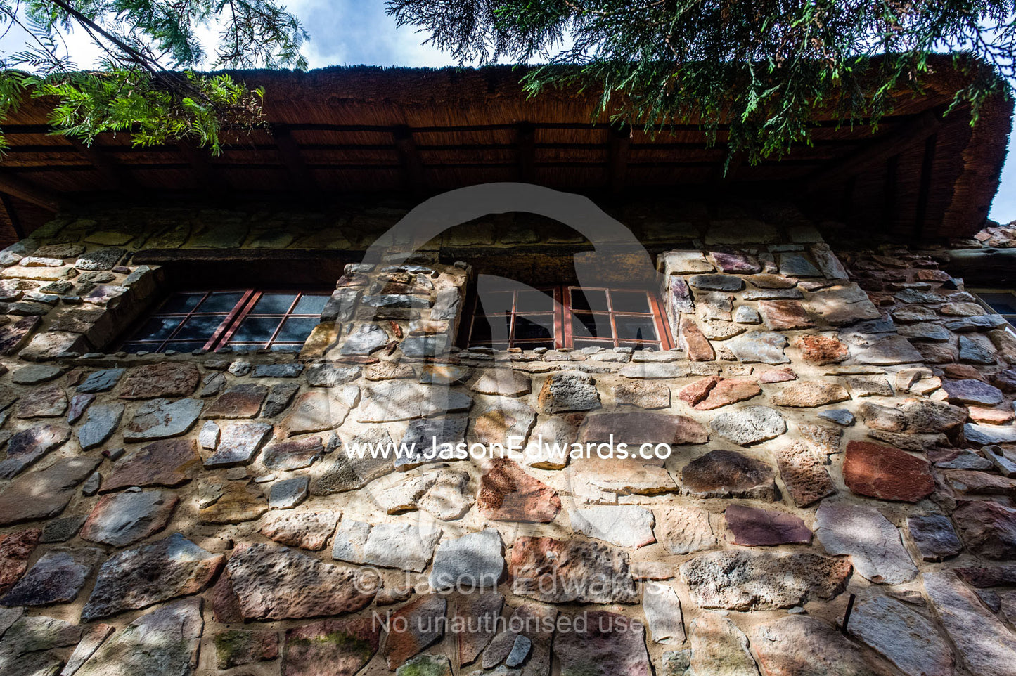 Dappled sunlight falls on a handmade stone wall in a safari lodge. The Farm Inn, Pretoria, Gauteng Province, South Africa.