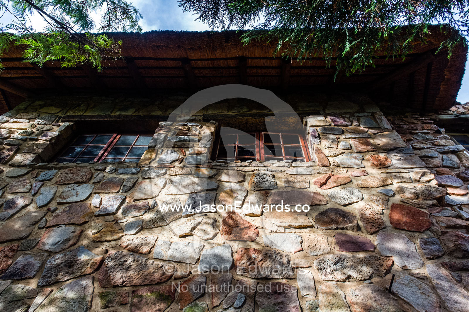 Dappled sunlight falls on a handmade stone wall in a safari lodge. The Farm Inn, Pretoria, Gauteng Province, South Africa.