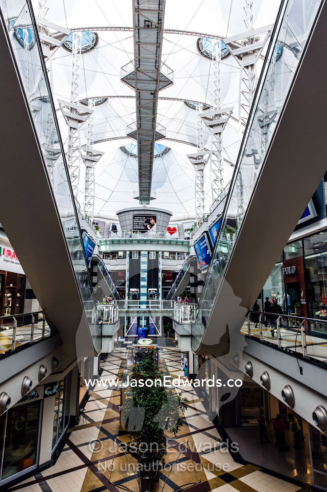 Enormous escalators connect levels in a sunlit shopping mall. Menlyn Park, Pretoria, Menlyn Mall, Pretoria, Gauteng Province, South Africa.