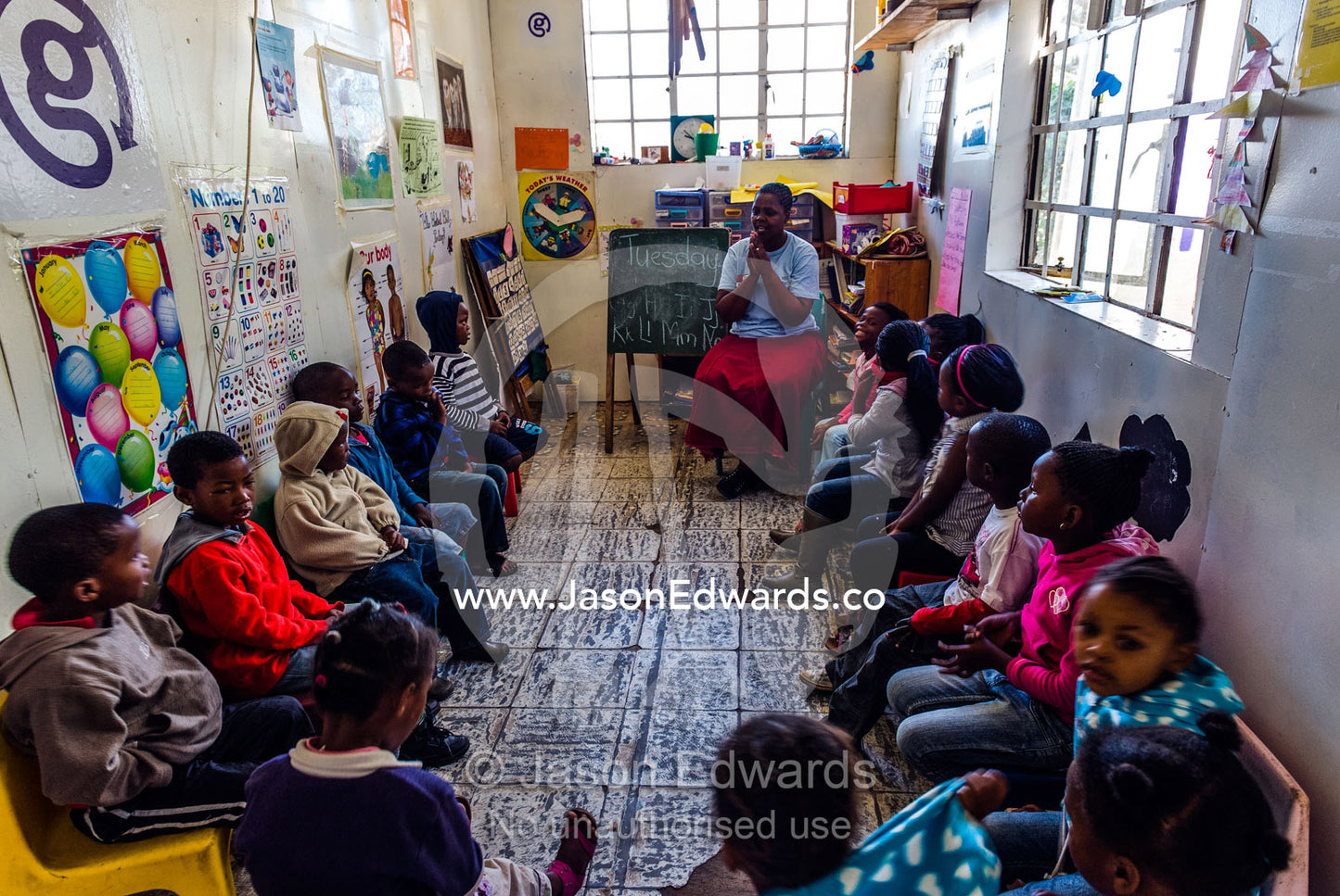 A teacher helps students with their math and alphabet at school. Red Hill Township and Pre-School, Cape Town, Western Cape, South Africa.