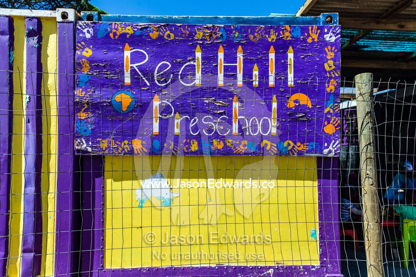 A bright purple and yellow Pre-school sign with childrens hand prints. Red Hill Township and Pre-School, Cape Town, Western Cape, South Africa.