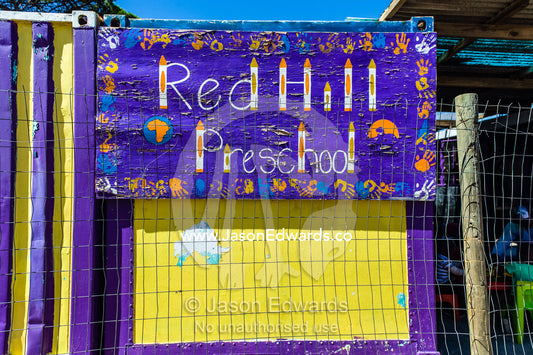 A bright purple and yellow Pre-school sign with childrens hand prints. Red Hill Township and Pre-School, Cape Town, Western Cape, South Africa.