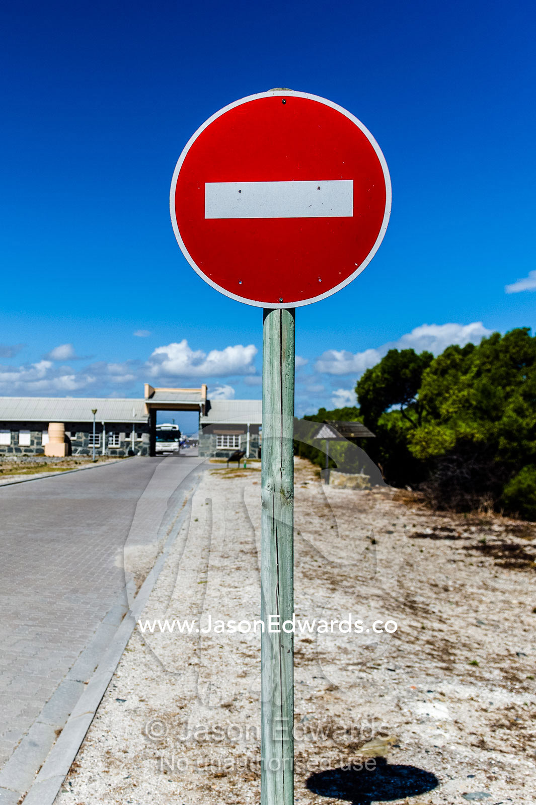 A bright red stop sign near the entrance to a prison museum. Robben Island, Cape Town, Bloubergstrand, Table Bay, Western Cape, South Africa.