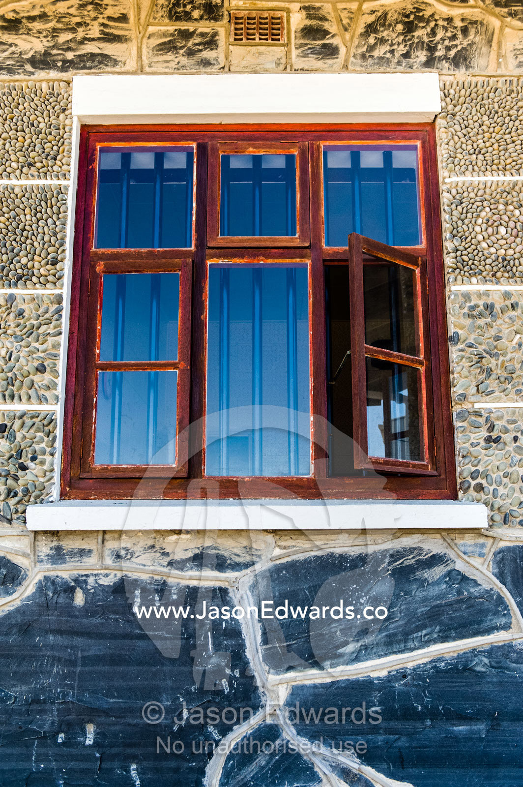 Prison bars visible through timber and glass window shutters. Robben Island, Cape Town, Bloubergstrand, Table Bay, Western Cape, South Africa.