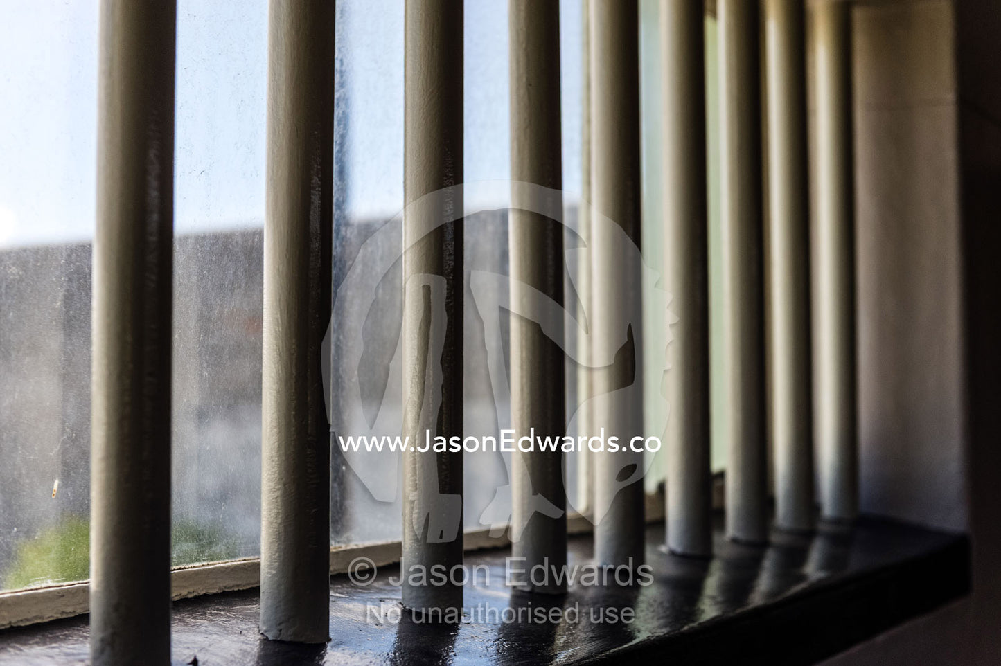 Sunlight catches stout steel bars in a prison cell. Robben Island, Cape Town, Bloubergstrand, Table Bay, Western Cape, South Africa.
