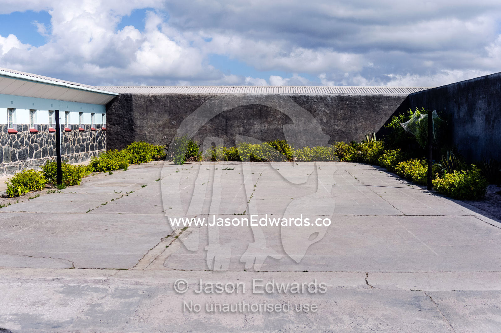A barren concrete exercise yard surrounded by prison cells. Robben Island, Cape Town, Bloubergstrand, Table Bay, Western Cape, South Africa.