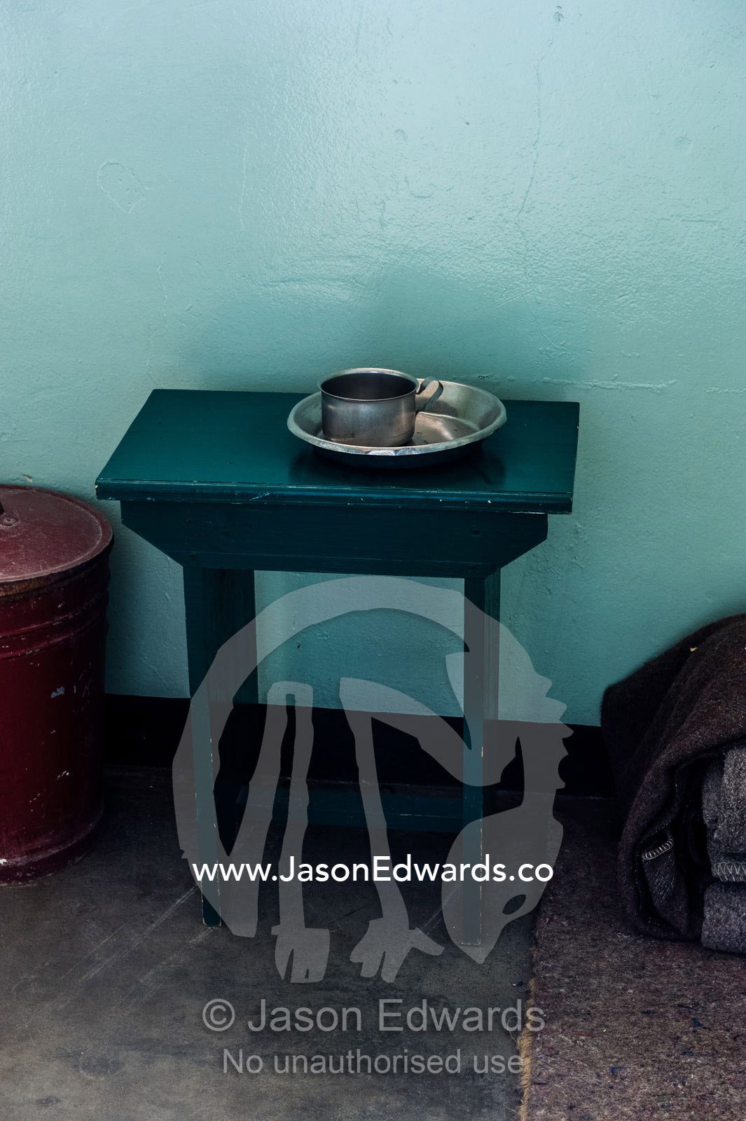 A table holds a cup and bowl in the cell inhabited by Nelson Mandela. Robben Island, Cape Town, Bloubergstrand, Table Bay, Western Cape, South Africa.