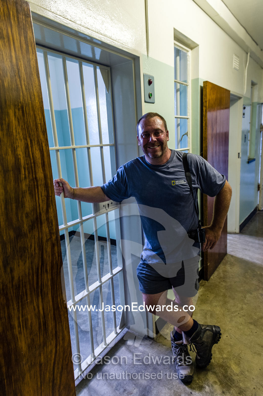 A visitor outside a prison cell on Robben Island. Robben Island, Cape Town, Bloubergstrand, Table Bay, Western Cape, South Africa.