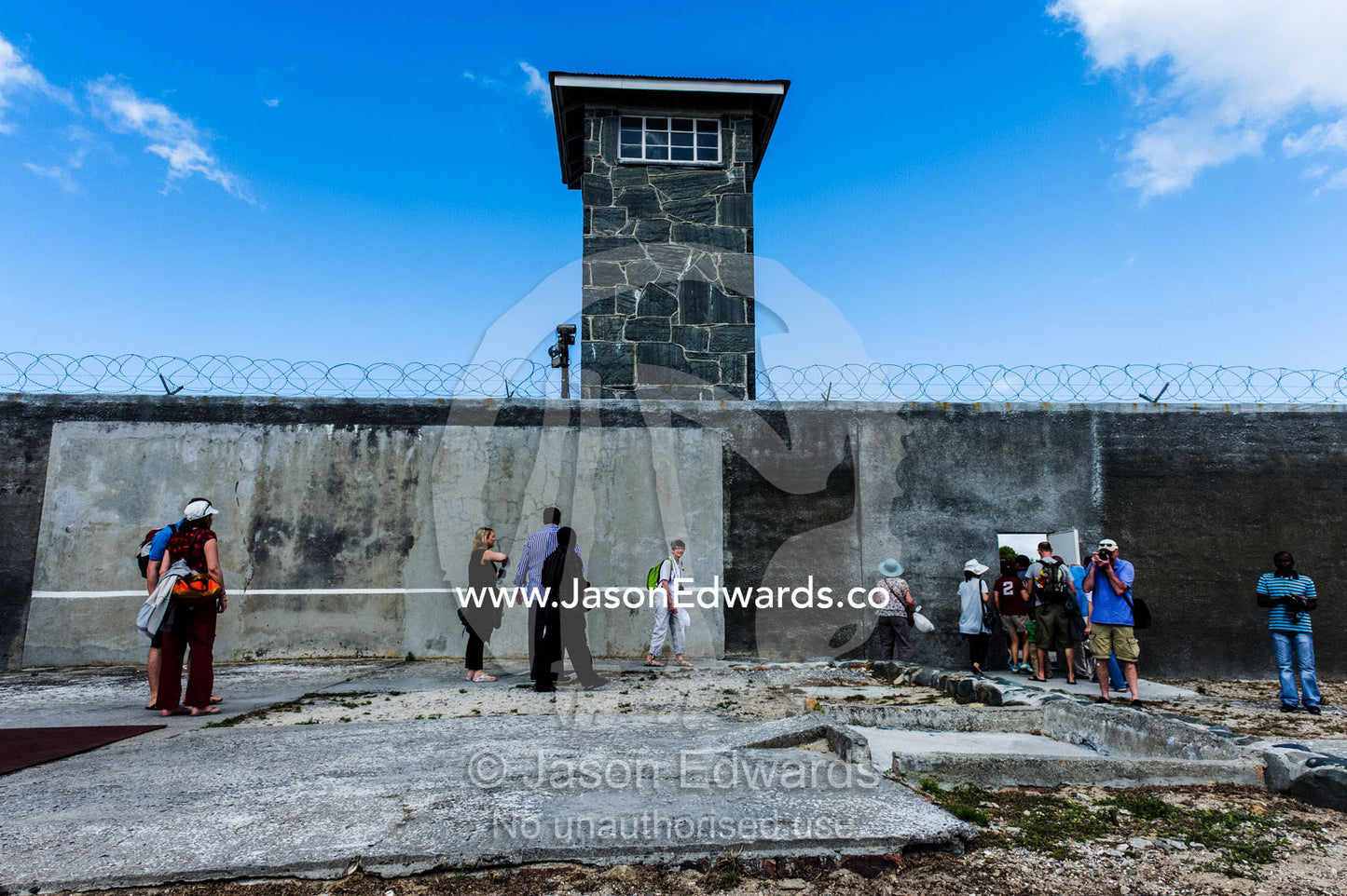 Tourists explore a prison yard on a tour of Robben Island. Robben Island, Cape Town, Bloubergstrand, Table Bay, Western Cape, South Africa.