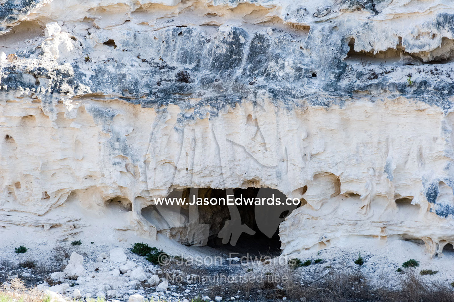 A cave-like tunnel entrance leads to a prison limestone quarry in a cliff. Robben Island, Cape Town, Bloubergstrand, Table Bay, Western Cape, South Africa.