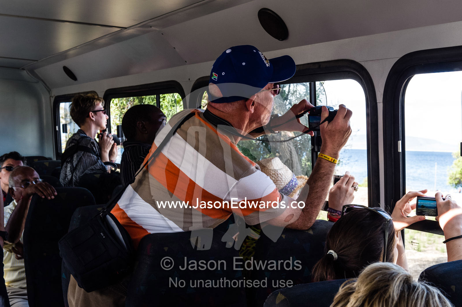 Tourists photograph historical prison museum sites from a tour bus. Robben Island, Cape Town, Bloubergstrand, Table Bay, Western Cape, South Africa.