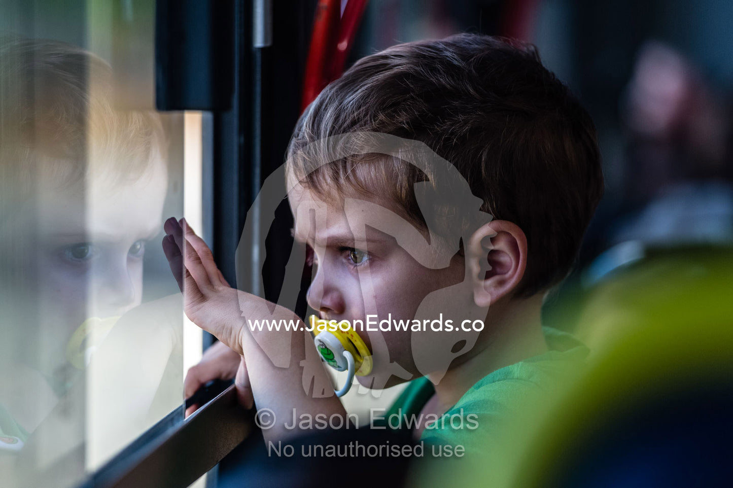 A small boy looks out of a bus window on a tour of a prison museum. Robben Island, Cape Town, Bloubergstrand, Table Bay, Western Cape, South Africa.
