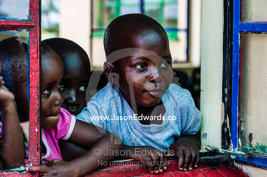 Children look out of a classroom window in a small African school. Kruger National Park, Manyeleti, Shalati Village, Mnisi Community, Limpopo, South Africa.