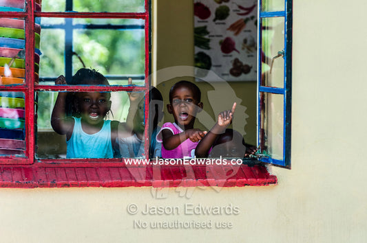 School children yelling goodbye from their classroom window. Kruger National Park, Manyeleti, Shalati Village, Mnisi Community, Limpopo, South Africa.
