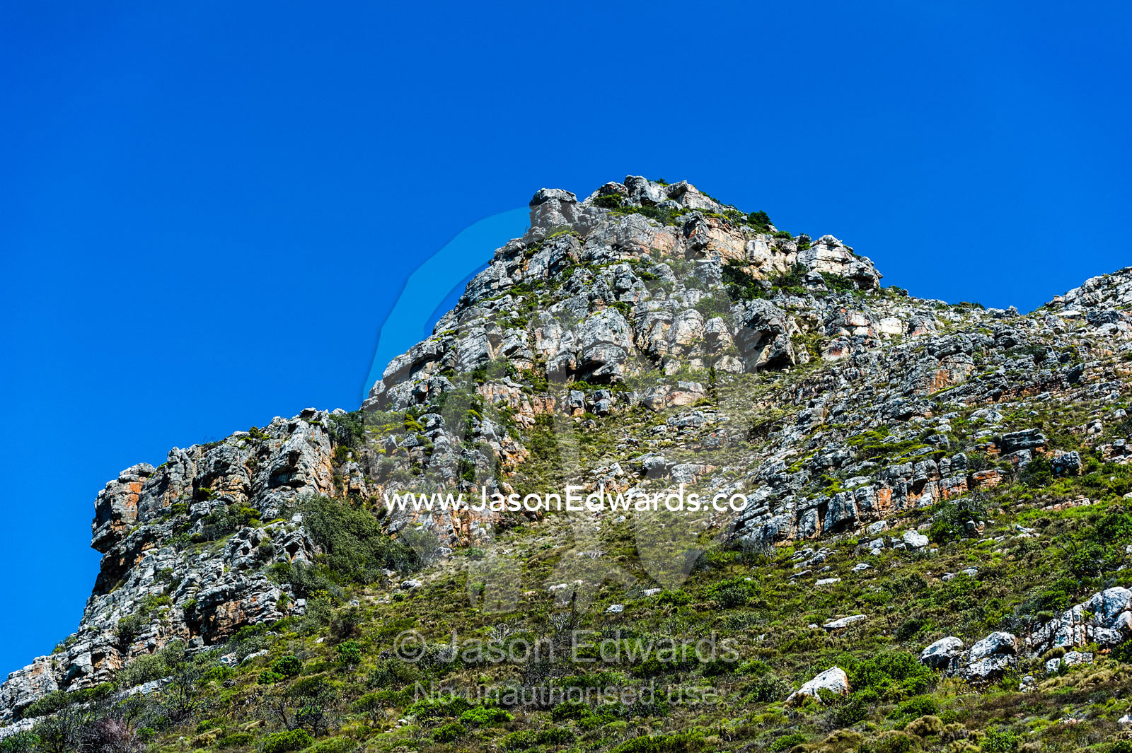 Rugged and weathered mountaintop boulders below a clear blue sky. Surfers Corner, Muizenberg, Cape Town, Chapmans Peak Drive, Western Cape, South Africa.
