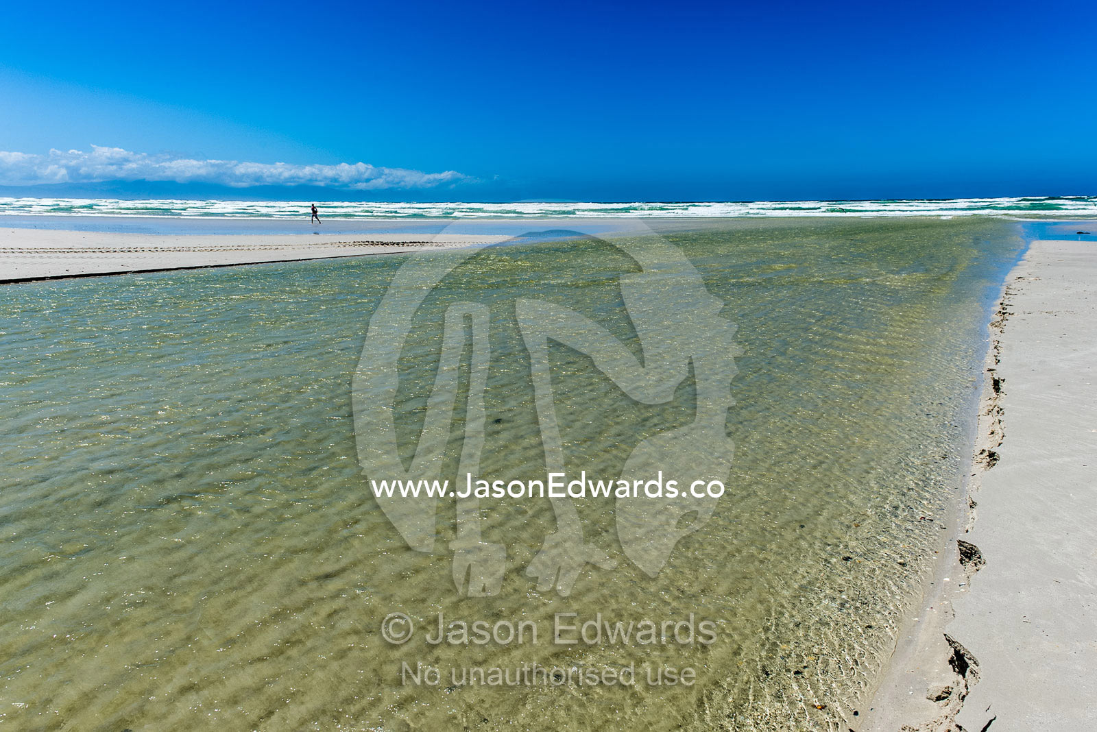 Freshwater from a mountain river flowing over a beach into the ocean. Surfers Corner, Muizenberg, Cape Town, Chapmans Peak Drive, Western Cape, South Africa.