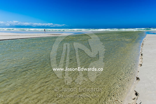 Freshwater from a mountain river flowing over a beach into the ocean. Surfers Corner, Muizenberg, Cape Town, Chapmans Peak Drive, Western Cape, South Africa.