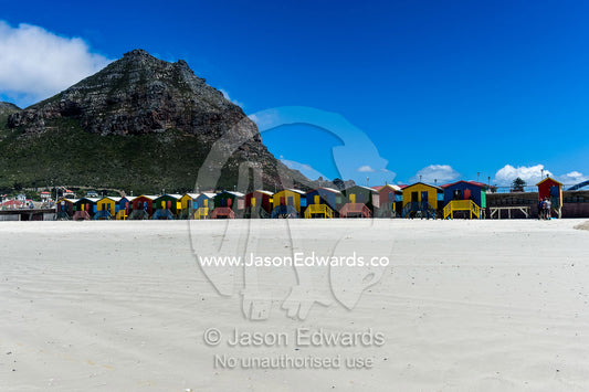 Brightly colored bathing boxes on stilts on the beach in summer. Surfers Corner, Muizenberg, Cape Town, Chapmans Peak Drive, Western Cape, South Africa.