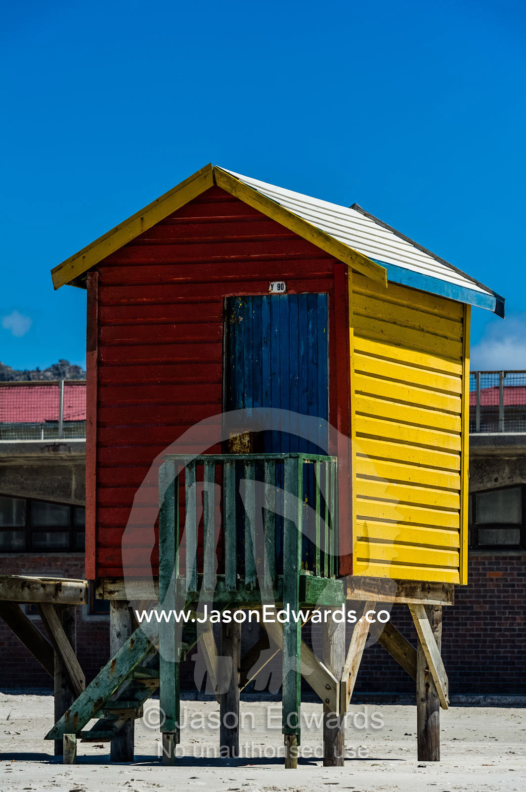 A brightly colored bathing box on stilts on the beach in summer. Surfers Corner, Muizenberg, Cape Town, Chapmans Peak Drive, Western Cape, South Africa.