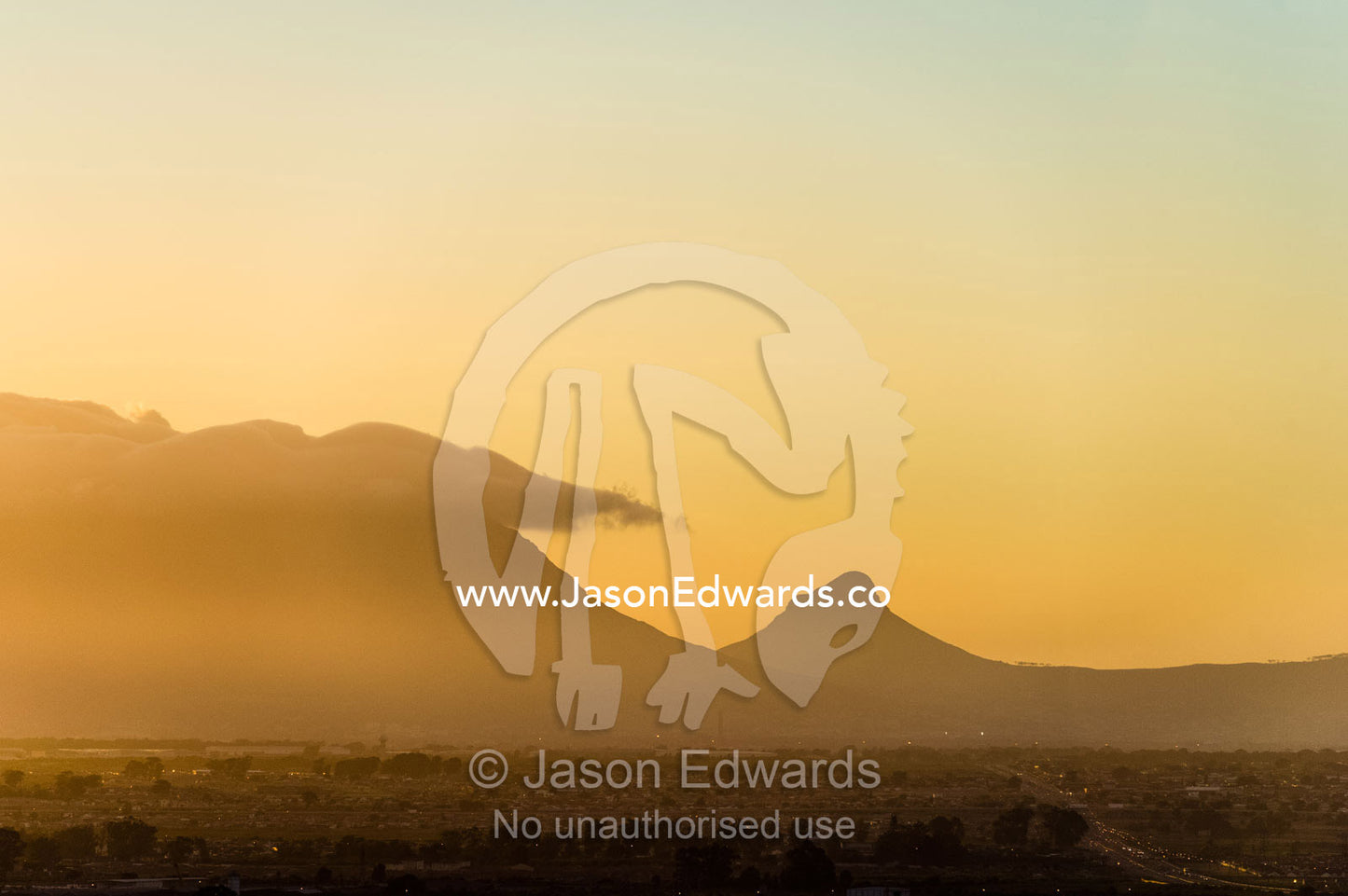 Table Mountain and the Lion's Head rise over farming land at sunset. Stellenbosch, Cape Town, Western Cape, South Africa.