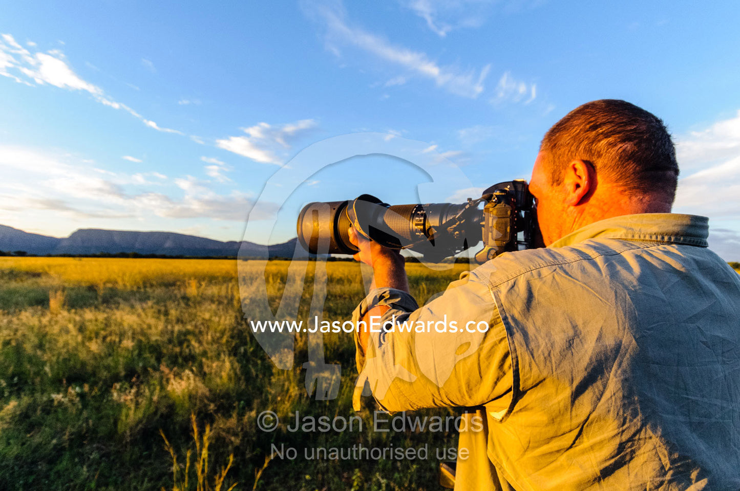 A photographer captures a savannah plain at sunset. Waterberg Mountains, Entabeni Game Reserve, Limpopo Province, South Africa.