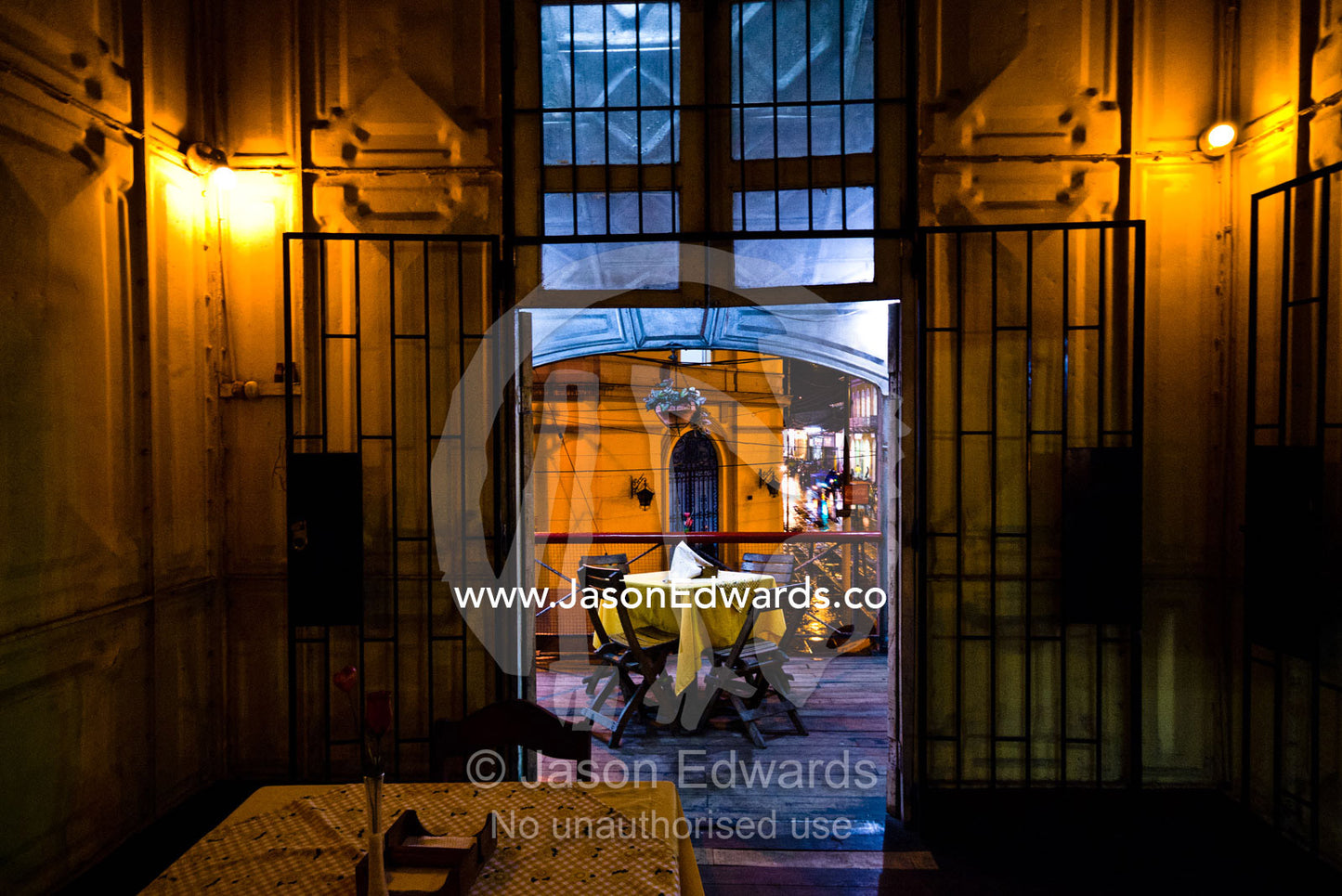 Looking through cast iron door to a dining table on the balcony of an antique steel restaurant. Iquitos, Amazon Basin, Loreto Region, Maynas Province, Peru.