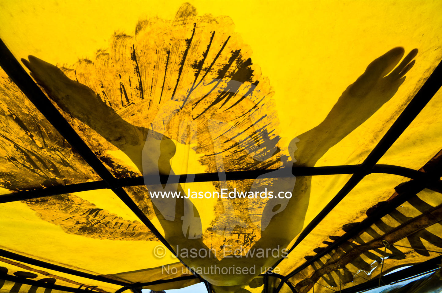 The silhouetted legs of a man sleeping on the tarpaulin roof of an Amazon River taxi. Amazon River, Amazon Basin, Loreto Region, Maynas Province, Peru.