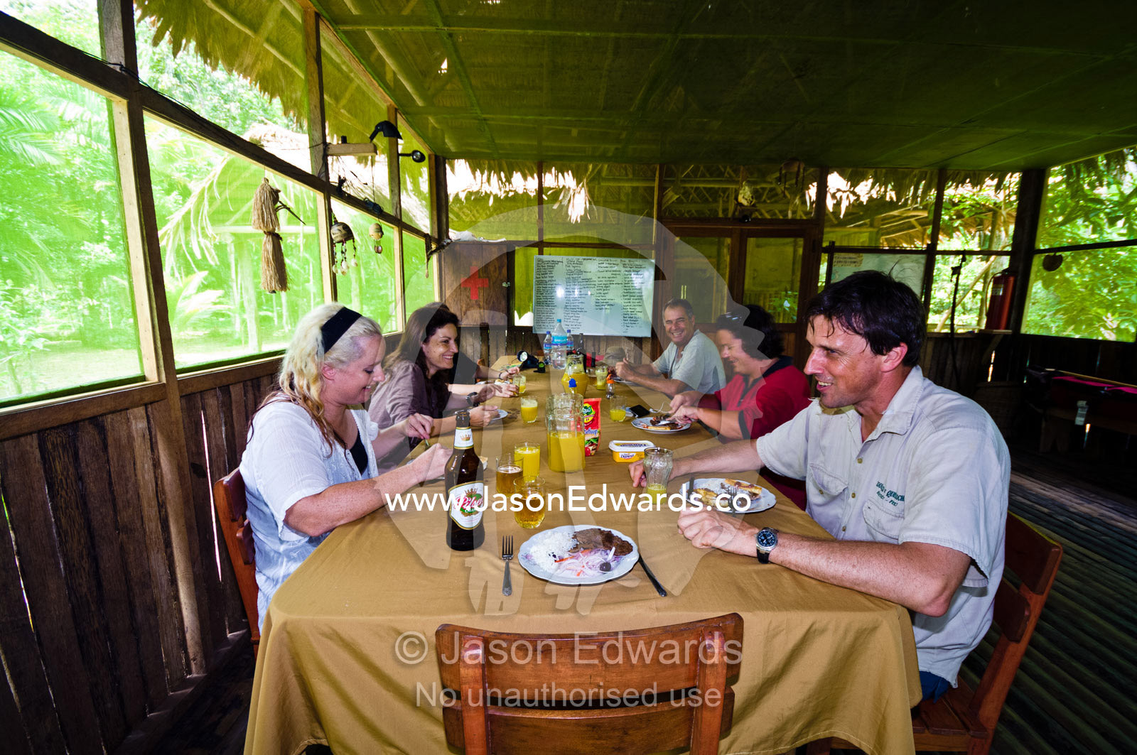 Tourists and conservation volunteers enjoying a meal in a lodge in the Amazon rainforest. Amazon River, Amazon Basin, Loreto Region, Maynas Province, Peru.