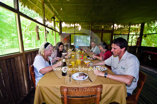 Tourists and conservation volunteers enjoying a meal in a lodge in the Amazon rainforest. Amazon River, Amazon Basin, Loreto Region, Maynas Province, Peru.