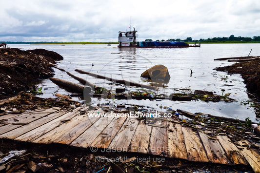 A barge with logs and pollution along the Amazon River. Puerto Masusa, Iquitos, Amazon River, Rio Amazonas, Amazon Basin, Loreto Region, Maynas Province, Peru.