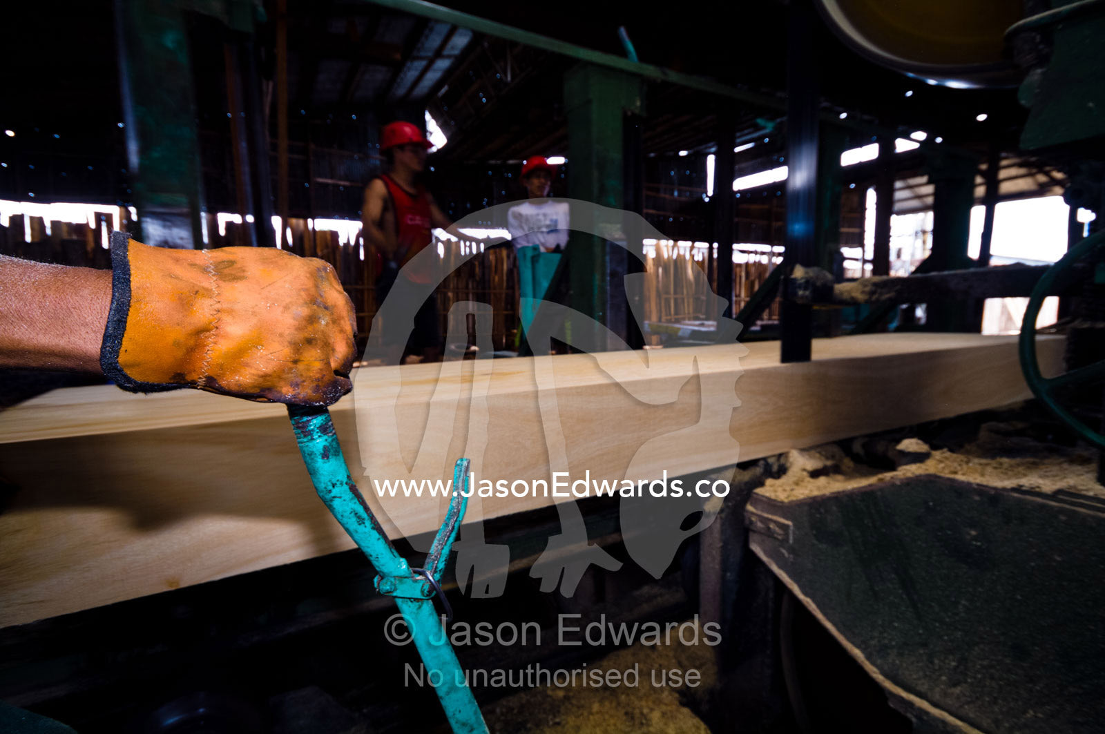 A laborer in a logging mill pulls the lever controlling the band saw trimming timber from a rainforest tree. Puerto Masusa, Iquitos, Amazon Basin, Loreto Region, Maynas Province, Peru.