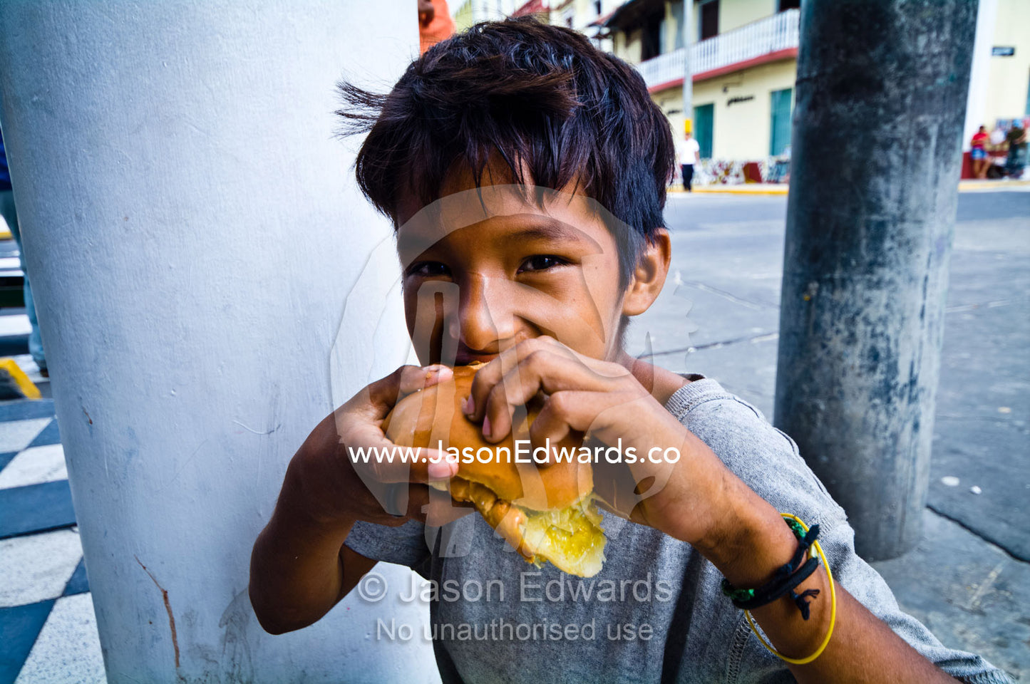 A boy enjoys eating a sandwich for lunch in an Amazon river town cafe. Plaza de Armas, Iquitos, Amazon Basin, Loreto Region, Maynas Province, Peru.